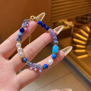 Detailed close-up of beaded bracelet with blue zircon stones and gold lobster clasp