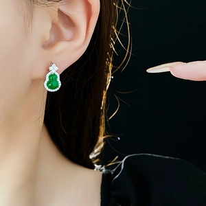 Macro view of a gourd-shaped green zircon earring set in silver, worn on the earlobe