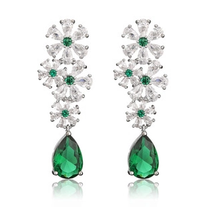 Gros plan de boucles d'oreilles en C argentées ornées de zircons blancs et verts