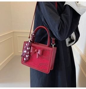 Detail of red wedding handbag featuring exquisite floral embroidery and a silk scarf handle