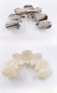 Close-up of wave-shaped acrylic hair claws in marble and jade patterns for women