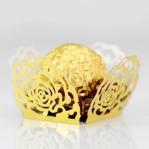 Close-up of golden hollow rose laser-cut paper holder for chocolate decoration