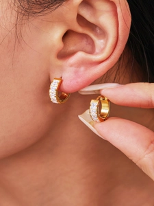 Close-up of golden huggie earrings with square-cut cubic zirconia inlays