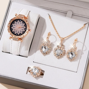 Close-up of rose gold watch set with crystal heart necklace, earrings and ring in a box