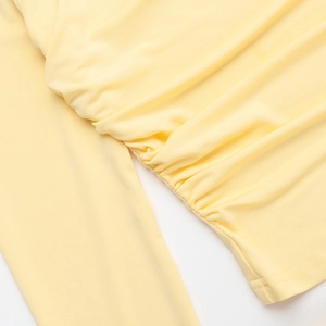 Detailed view of ruched side seams and textured fabric on light yellow slim fit skirt set