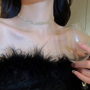 Detailed view of a gold choker necklace with sparkling rhinestones worn by a model