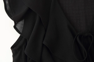 Close-up of black ruffled chiffon fabric texture with delicate lace-up neck detailing