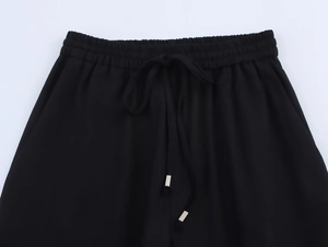 Détail du pantalon en lin noir avec taille élastique et cordons à embouts argentés