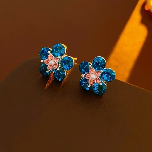 Elegant gold flower earrings with deep blue rhinestones and a central white pearl detail