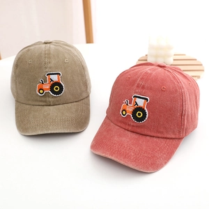 Detail of tractor embroidery on washed cotton baseball caps in khaki and vintage red