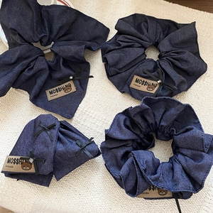 Detail of blue denim hair scrunchies with leather bear tags and silk bow accents
