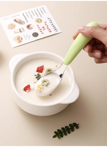 Close-up of baby self-feeding spoon with 316L stainless steel head and green handle