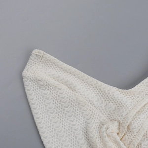 Gros plan sur la dentelle texturée blanc cassé avec motifs ajourés et coutures précises