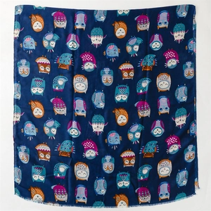 Detail shot of navy blue scarf with colorful cartoon owl patterns in cotton-linen fabric