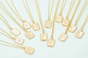 Gold initial pendant necklace set with sparkling cubic zirconia on a light background