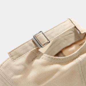 Detail of beige cotton baseball cap featuring adjustable strap with silver metal buckle