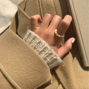 Detail of elegant 925 sterling silver heart ring and pearl band on warm knit background