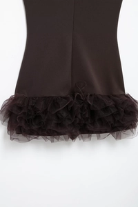 Detail of layered brown mesh ruffles on the hem of a sleeveless bodycon mini dress
