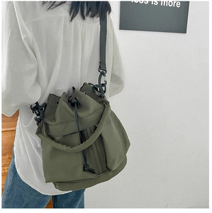 Detailed back view of a person wearing an army green nylon drawstring bucket shoulder bag