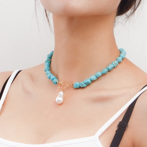 Close-up of bohemian turquoise bead necklace with a baroque pearl pendant and gold toggle clasp