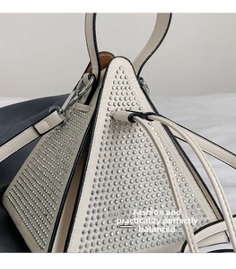 Detail of white triangular evening bag with rhinestone embellishments and black piping
