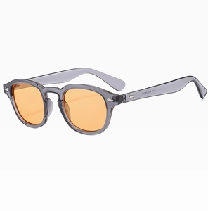 Close-up of retro round sunglasses with transparent grey frame and orange lenses