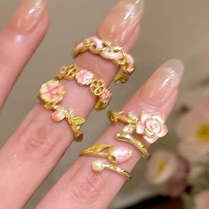 Close-up of 18k gold plated flower rings with pink enamel and pearl on model's hand