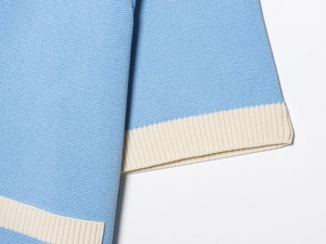 Detail of sky blue and cream contrast knit fabric showing high-density stitching and texture