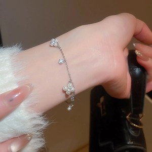 Detail of silver clover pearl bracelet with zircon stones on female wrist