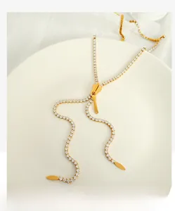 Detailed view of long gold zipper necklace with pave-set crystals on white platter