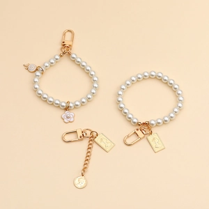 Detail of vintage pearl keychains with gold Queen Elizabeth coin and flower charms