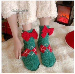Détail de chaussettes en polaire corail verte avec nœuds rouges et motifs festifs