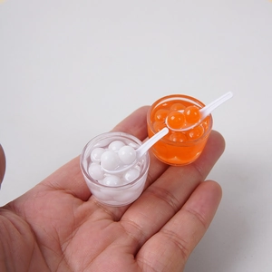 Miniatuur dessertkom model met kleurrijke parels en een kleine witte lepel erbij