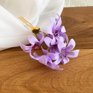 Detailed close-up of a purple fabric flower hair pin with a gold metal U-shaped fork