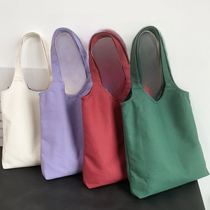 Detail showing solid color canvas tote bags in white, purple, red, and green colors