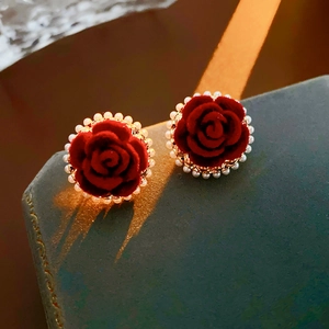 Vue détaillée des boucles d'oreilles fleur velours rouge et perles sur écrin de luxe