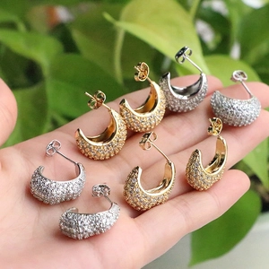Close-up of sparkling gold and silver C-shaped stud earrings with micro-paved zircons