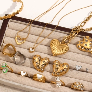Detail of heart-shaped gold and silver necklaces with zircon and white enamel in a tray