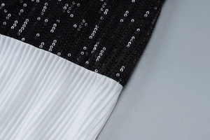 Macro detail of black sequins and white pleated fabric on a backless summer dress