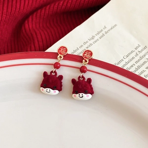 Close-up of red flocked calf earrings with golden Fu character studs on ceramic plate