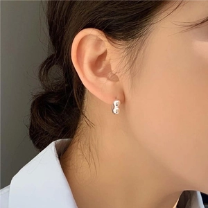 Close-up of a minimalist silver double hoop earring worn by a model in a lifestyle shot