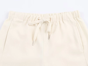 Dettaglio dell'elastico in vita con coulisse beige e punte in metallo dei pantaloncini