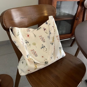 Floral canvas tote bag with plant prints resting on a vintage wooden chair