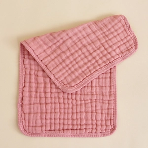 Detail view of pink muslin cotton baby burp cloth with quilted texture and hemmed edges
