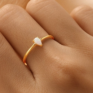 Macro shot of gold teardrop opal ring on finger showcasing elegant minimalist design
