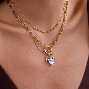 Close-up of double layer gold Figaro chain with blue heart ceramic pendant for women