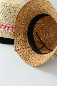 Close-up of straw sun hats with lace trim, ruffled edges and adjustable inner band