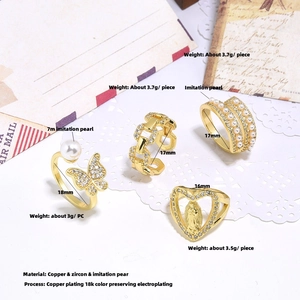 Flat lay of four gold-plated copper rings with zircon and pearls on vintage paper background