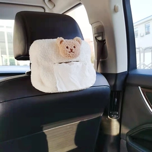 Close-up of white fleece car tissue holder with brown teddy bear on seat back
