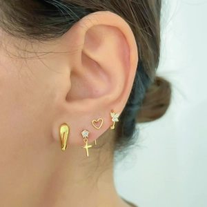 Close-up of gold cross and butterfly earrings set with cubic zirconia on model